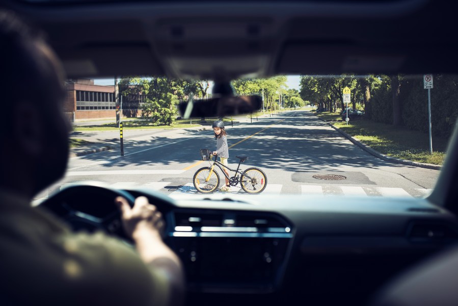 driver looking at child walking with a bicycle