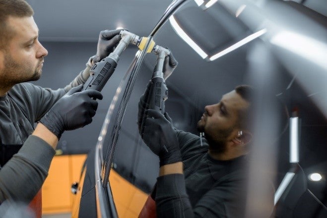 A person polishing the windshield of a vehicle at a service center in Miami, FL