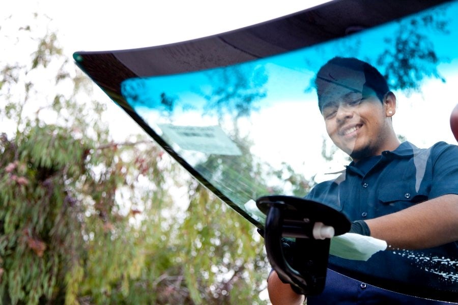 A person cleaning the windshield of a vehicle at a service center in Miami, FL